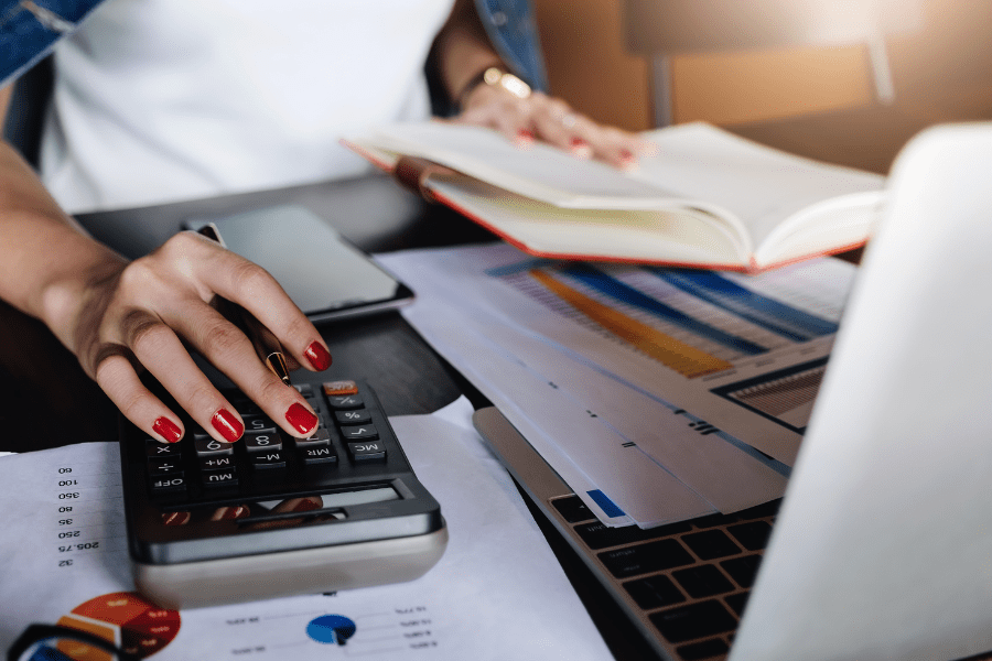 mujer utiliza calculadora, una libreta y un ordenador para preparar los impuestos de la empresa